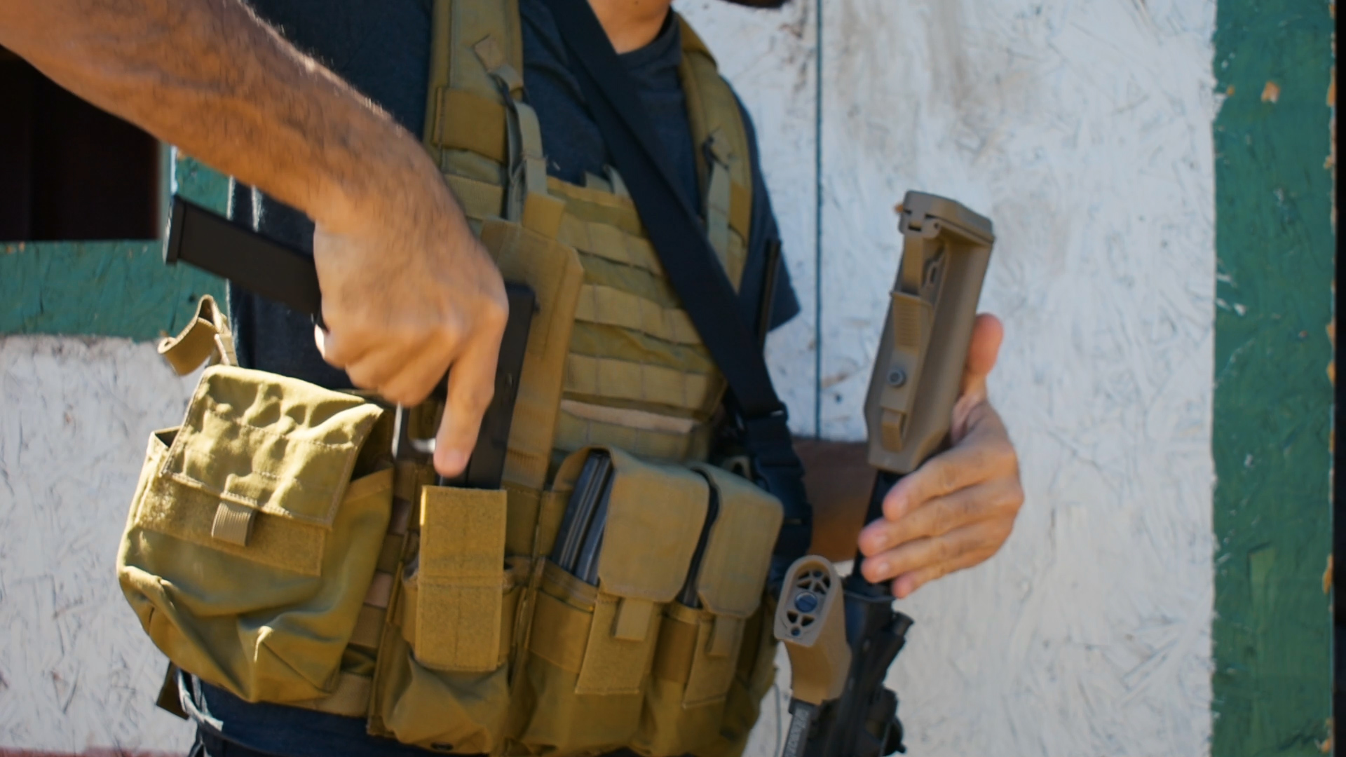 Airsoft player wearing tactical vest with attached pistol holster and magazine pouches